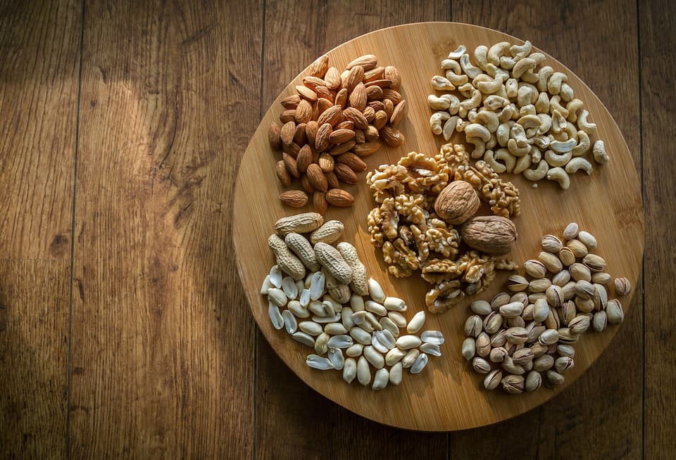 Walnuts, almonds, cashews and pistachios on a round wooden board (illustrative)