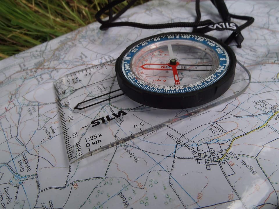 A walking compass resting on a paper map (illustrative)